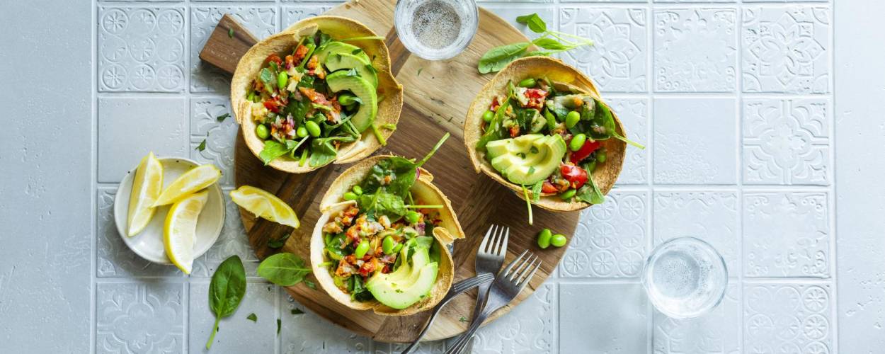 Avocado, Edamame auf Wraps mit Zitrone und Gabeln auf Holzbrett