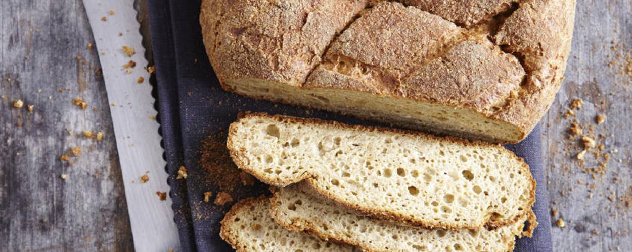 Brotlaib teilweise aufgeschnitten auf blauem Tuch mit Brotmesser