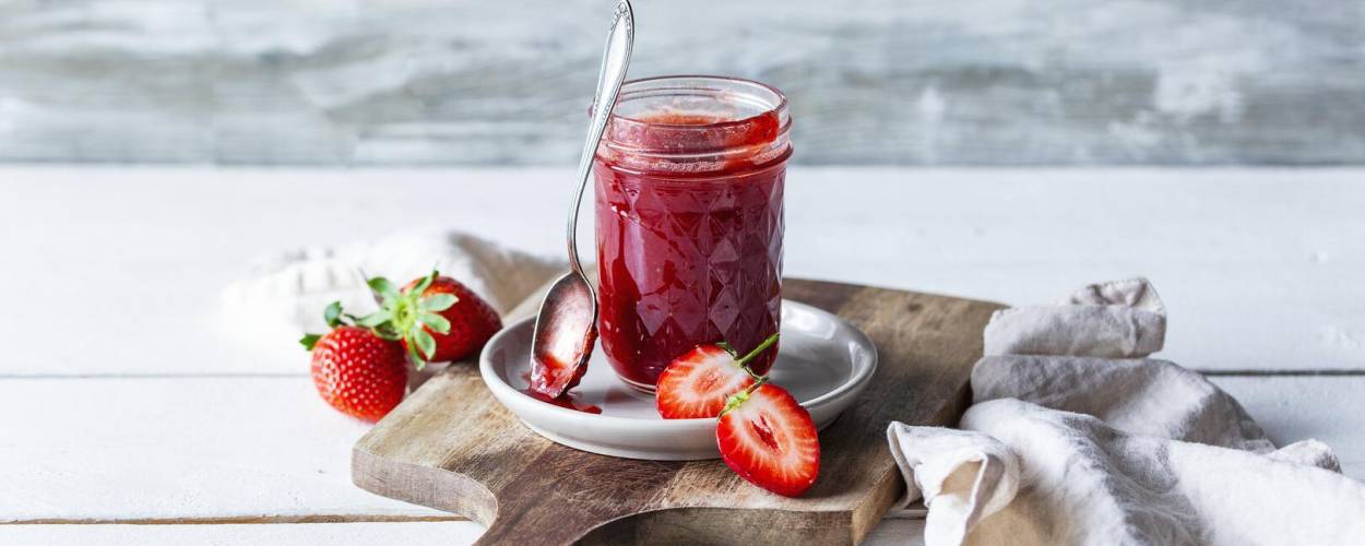 Rote Marmelade im Weckglas mit Erdbeeren auf Teller