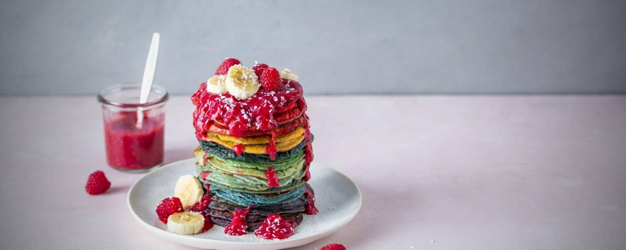 Regenbogenpfannkuchen mit Banane und Himbeeren