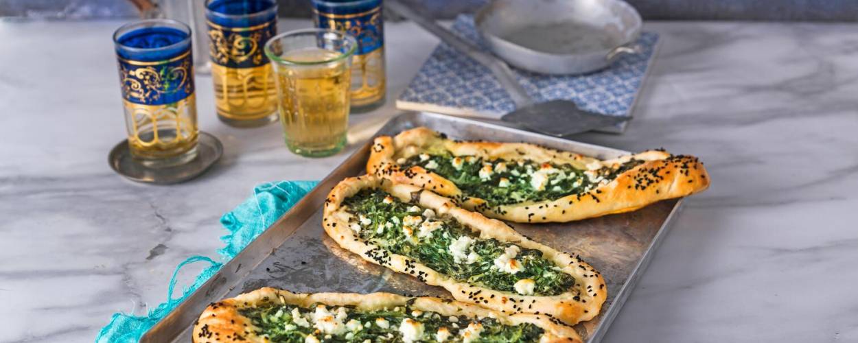 Spinat-Pide auf Blech mit Tee in Gläsern