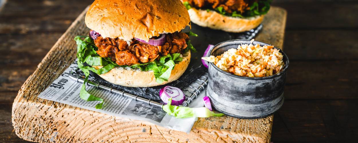 Burger mit crispy Patty, roten Zwiebeln und Salat auf Brett