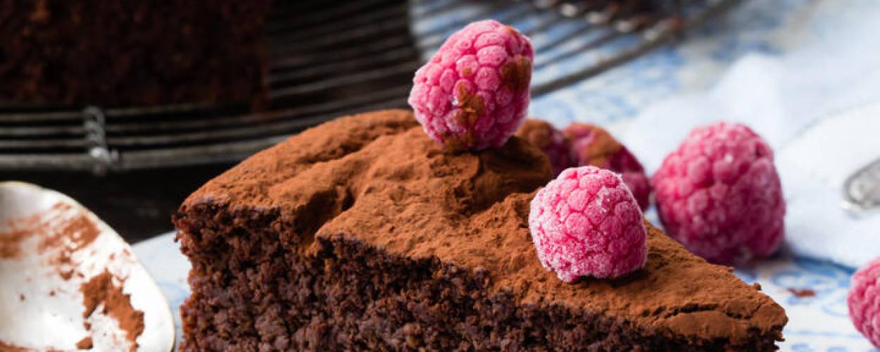 Schokoladenkuchen auf Gitter und ein Stück auf Teller mit Himbeeren