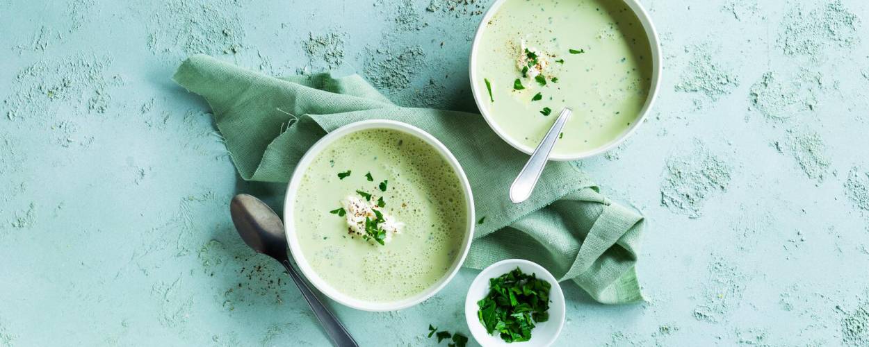 Bärlauchsuppe mit frischen Kräutern auf grünblauer Arbeitsplatte