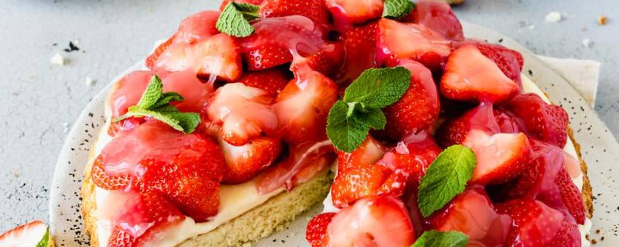 Erdbeerkuchen mit weißer Creme auf grauem Teller