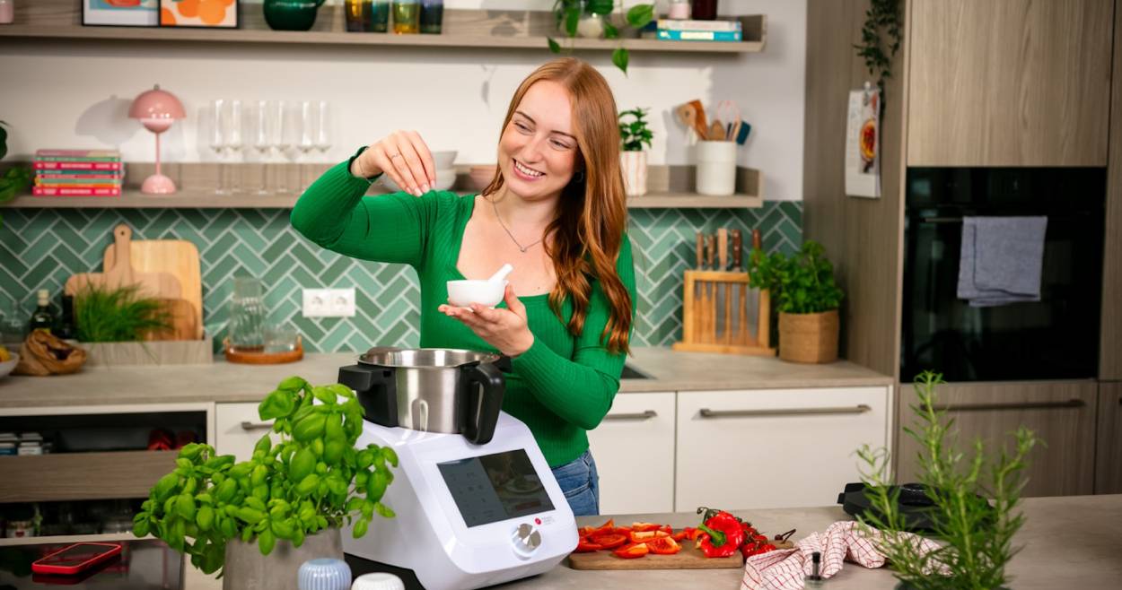 Eine junge Frau gibt etwas in den Monsieur Cuisine