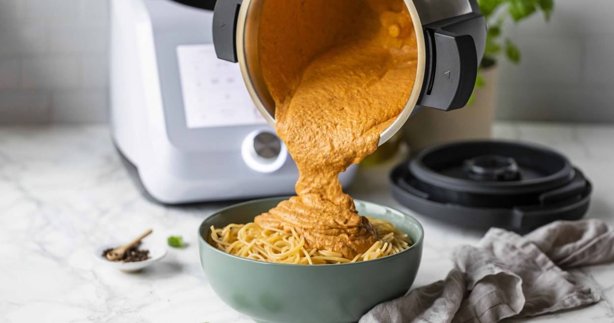 Dicke Tomatensoße wird auf eine Schüssel mit Spaghetti gekippt