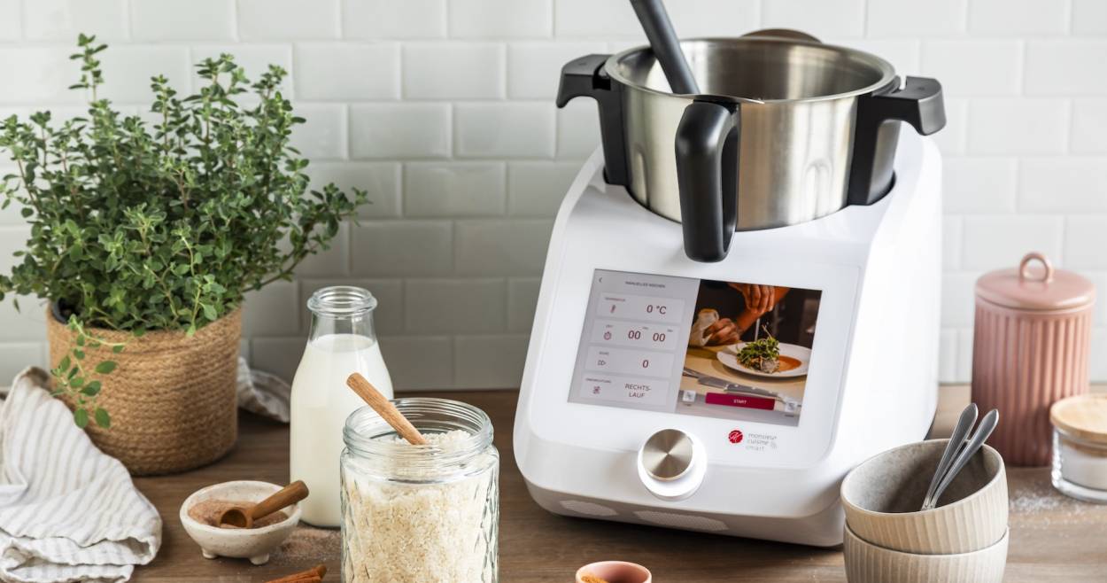 Monisieur Cuisine umgeben von Zutaten zum Kochen
