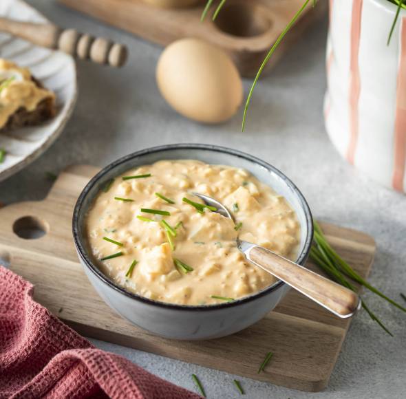 Eiersalat in einer Schale und auf Broten