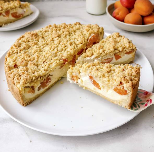 Kuchen angeschnitten mit Schmand, Aprikosen und Streuseln
