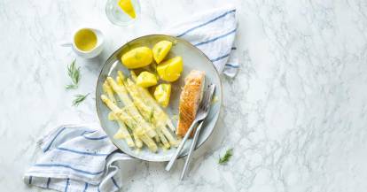 Runder Teller mit weißem Spargel, gekochten Kartoffeln und Lachsfilet