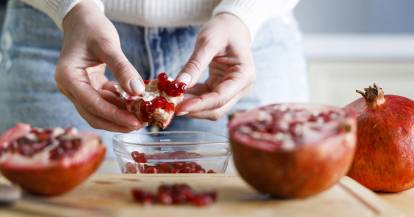 Granatapfel wird über einer Glasschüssel entkernt