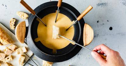Ein Stück Brot wird ins Käsefondue getunkt.