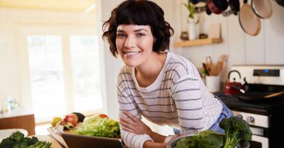 Frau lehnt auf einer Kücheninsel und lächelt in die Kamera