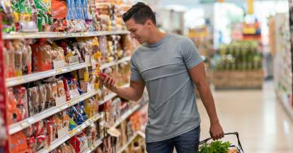 Junger Mann im Supermarkt vor einem Regal mit Lebensmitteln