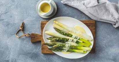 Weiße und grüne Spargelstangen mit Sauce hollandaise auf ovalem Teller