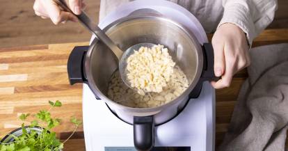 Spätzle werden mit einer Schöpfkelle aus dem Mixtopf genommen.