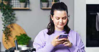 Judith mit einem Smartphone in der Hand vor dem Monsieur Cuisine
