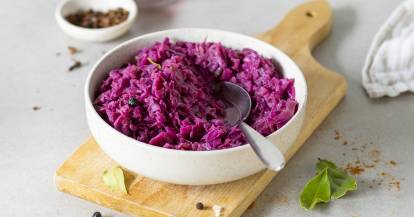 Rotkohl in einer Schale mit Löffel auf einem Holzbrett.