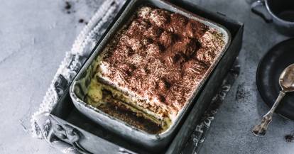 Tiramisu in einer Schale auf einem gedeckten Tisch.