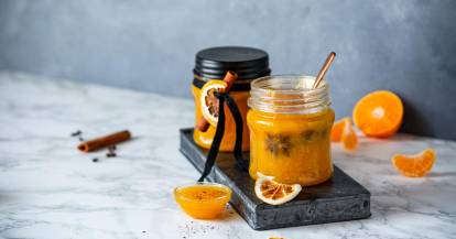 Orange Marmelade mit Glitzer in Glas mit Mandarinen und Zimt