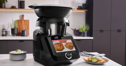 Monsieur Cuisine smart in der Black Edition auf einer Arbeitsplatte, daneben Kartoffelpuffer auf einem Teller.