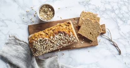 Angeschnittenes Brot mit Körnern auf einem Brettchen. 