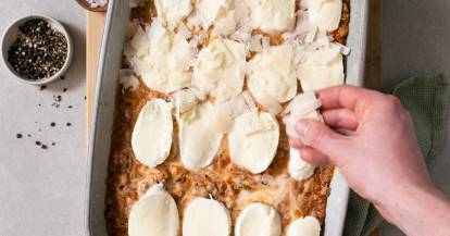Käse wird über eine Lasagne gegeben