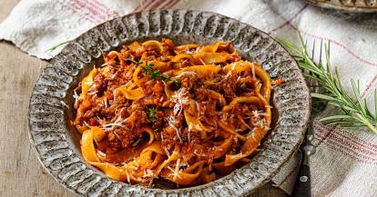 Tagliatelle mit Bolognese auf einem Teller mit angelegter Gabel