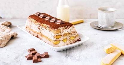 Tiramisu auf weißer Platte mit Kinderschokolade und Löffelbiskuit und Milch