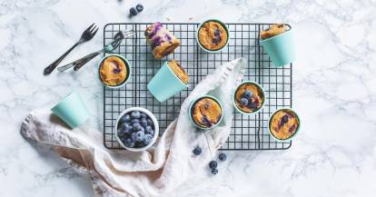 Blaubeermuffins auf Gitter mit Blaubeeren in Schale