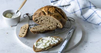 Dinkelbrot angeschnitten, eine einzelne Scheibe mit Quark davor