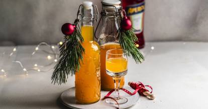 Zwei Flaschen mit orangefarbenem Likör, daneben ein Glas
