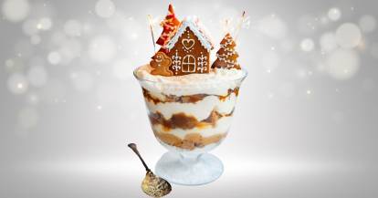 Ein Glas mit Schichtdessert, dekoriert mit einem Lebkuchenhaus