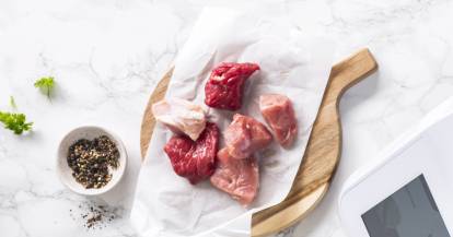 Fleischstücke auf einem Brett mit Butterbrotpapier