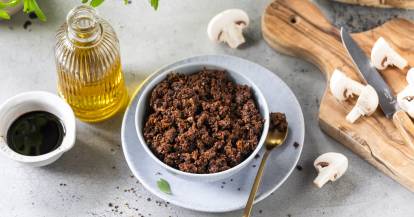 Eine Schale mit veganem Hack von oben fotografiert, daneben ein Brett mit Champignons