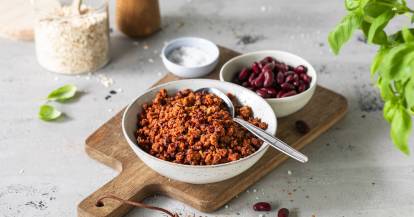 Veganes Hack in einer grauen Schale auf einem Holzbrett, danaben eine Schale mit Kidneybohnen