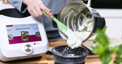 Jemand holt einen Dip mit einem Spatel aus dem Topf des Monsieur Cuisine