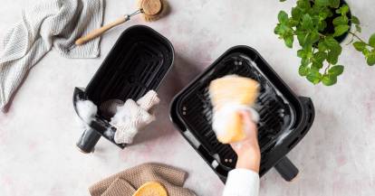 Jemand reinigt die Schale der Heißluftfritteuse mit einem Schwamm