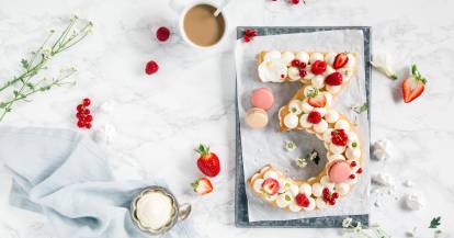 Ein Kuchen in Form der Zahl 3 mit Früchten und Maccarons, von oben fotografiert