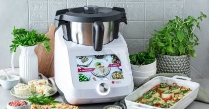 Der Monsieur Cuisine, daneben eine Auflaufform und Töpfe mit Kräutern