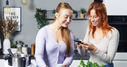 Zwei Frauen stehen neben dem Monsieur Cuisine und schauen auf ein Smartphone