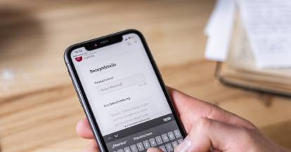 Jemand hält ein Smartphone, dahinter steht der Monsieur Cuisine