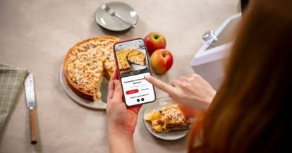 Eine Frau hält ein Smartphone, darauf ein Apfelkuchen