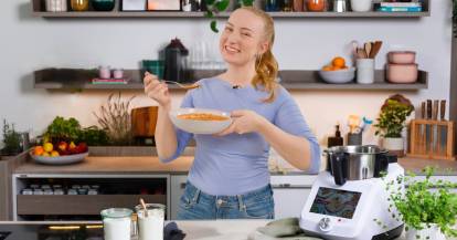 Junge Frau mit einem Teller Suppe neben dem Monsieur Cuisine