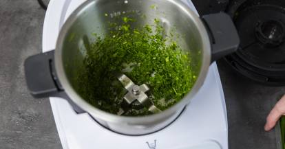 Blick in den Monsieur Cuisine Mixbehälter, darin zerkleinerte Kräuter