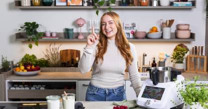 Junge Frau neben Monsieur Cuisine, zeigefinger erhoben