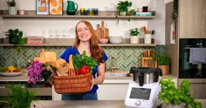 Junge Frau mit einem Korb voll Gemüse in einer Küche, neben dem Thermomix®