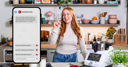 Junge Frau neben Monsieur Cuisine und einem Screenshot aus der ZauberMix App mit dem Schriftzug Chatbot Emma