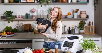 Junge Frau umarmt den Mixbehälter des Monsieur Cuisine